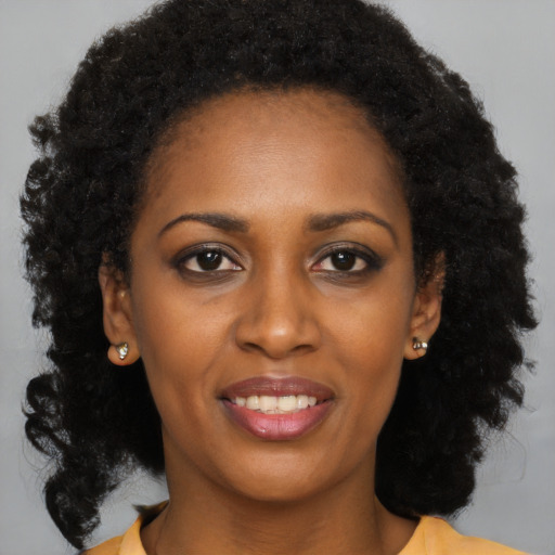 Joyful black young-adult female with long  brown hair and brown eyes
