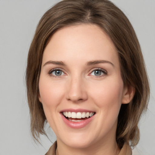 Joyful white young-adult female with medium  brown hair and grey eyes