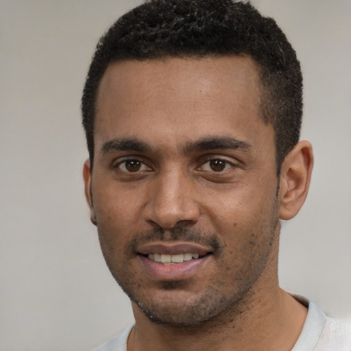 Joyful black young-adult male with short  brown hair and brown eyes