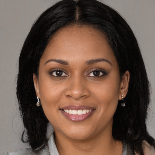 Joyful black young-adult female with long  black hair and brown eyes