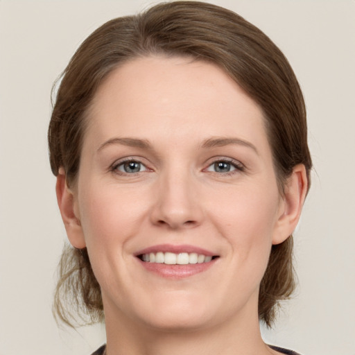 Joyful white young-adult female with medium  brown hair and grey eyes