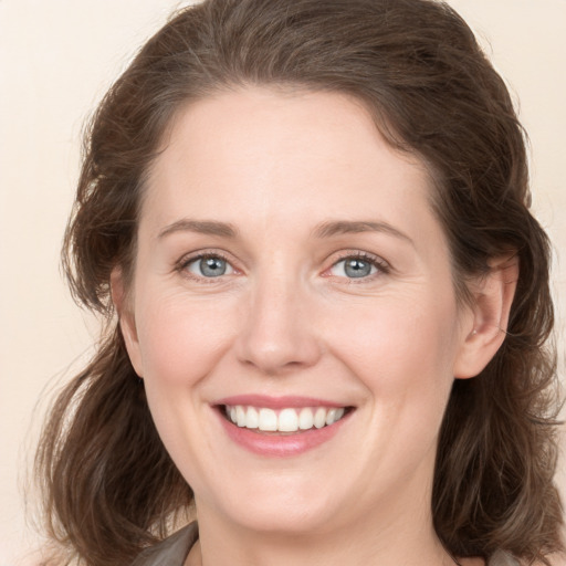 Joyful white young-adult female with medium  brown hair and grey eyes