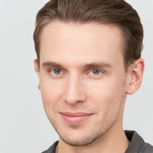 Joyful white young-adult male with short  brown hair and grey eyes