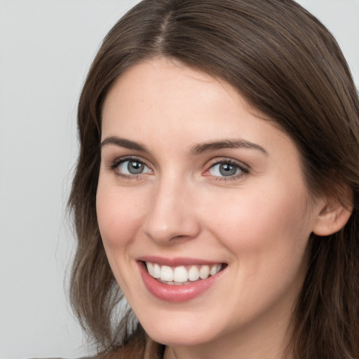 Joyful white young-adult female with long  brown hair and grey eyes