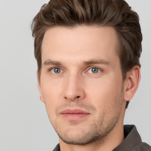 Joyful white young-adult male with short  brown hair and grey eyes