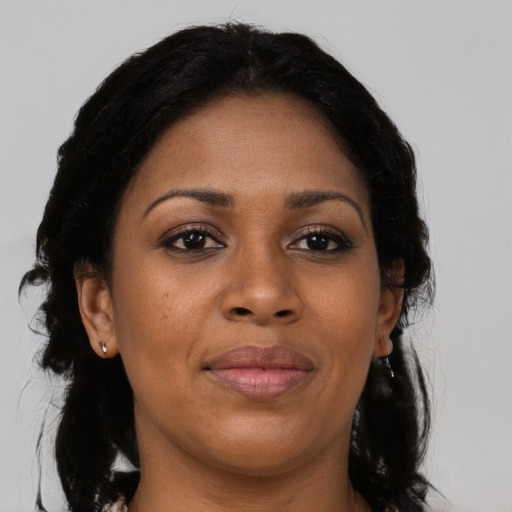 Joyful black adult female with long  black hair and brown eyes