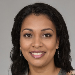 Joyful black young-adult female with long  brown hair and brown eyes