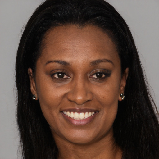 Joyful black young-adult female with long  brown hair and brown eyes
