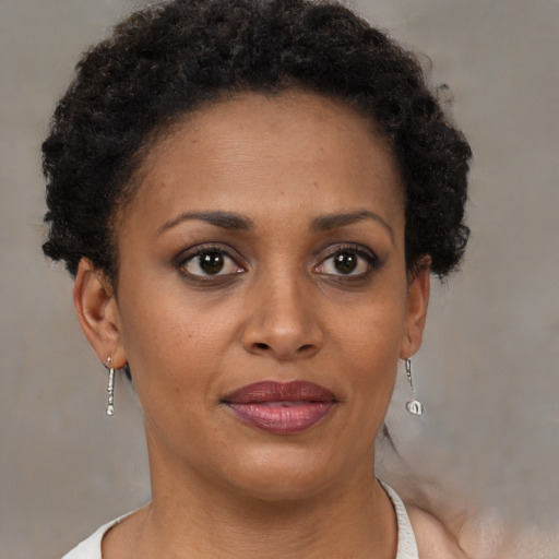 Joyful black young-adult female with short  brown hair and brown eyes