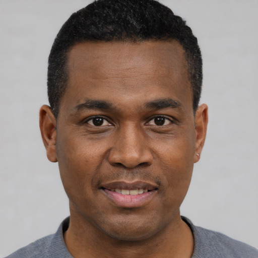 Joyful black young-adult male with short  black hair and brown eyes