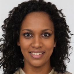 Joyful black young-adult female with long  brown hair and brown eyes