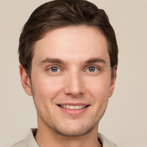 Joyful white young-adult male with short  brown hair and grey eyes