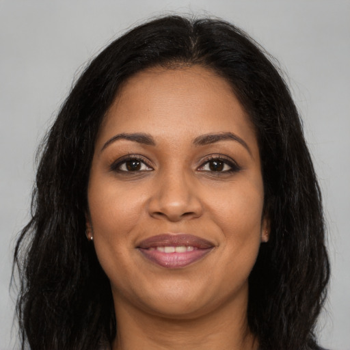 Joyful black young-adult female with long  brown hair and brown eyes