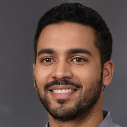 Joyful latino young-adult male with short  black hair and brown eyes