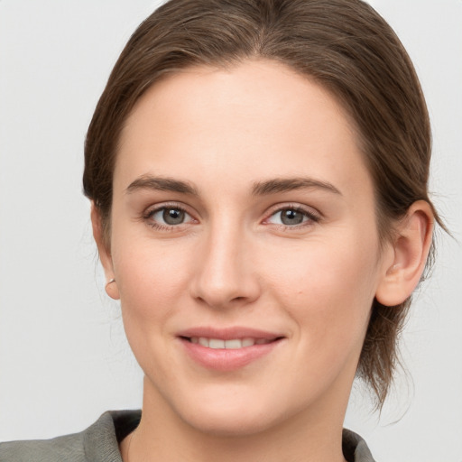 Joyful white young-adult female with medium  brown hair and grey eyes