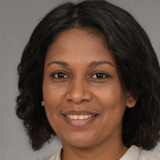 Joyful black adult female with medium  brown hair and brown eyes