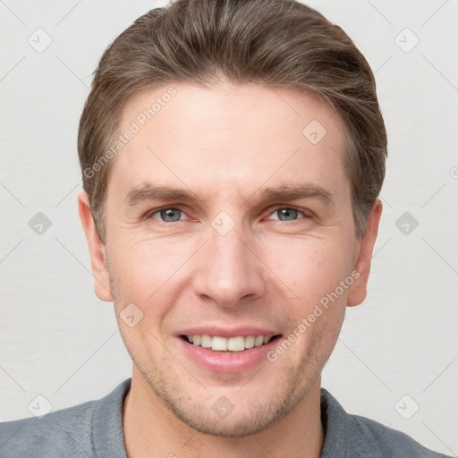 Joyful white young-adult male with short  brown hair and grey eyes