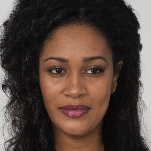Joyful black adult female with long  black hair and brown eyes