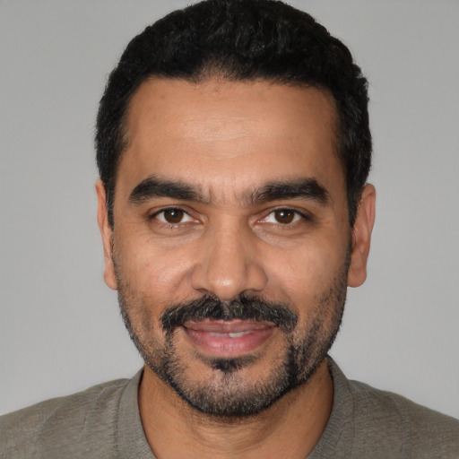 Joyful latino young-adult male with short  black hair and brown eyes
