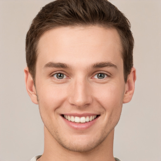 Joyful white young-adult male with short  brown hair and grey eyes