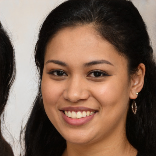 Joyful latino young-adult female with long  brown hair and brown eyes