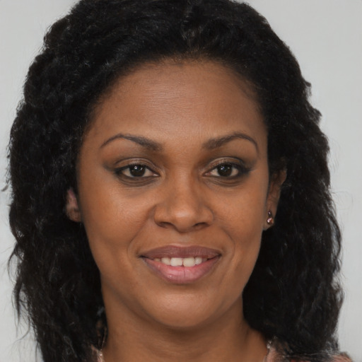 Joyful black young-adult female with long  brown hair and brown eyes