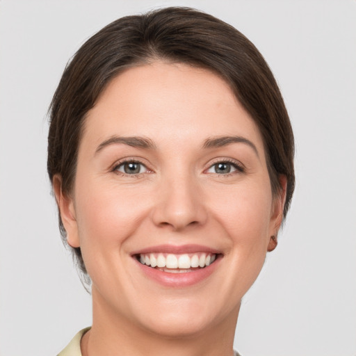 Joyful white young-adult female with short  brown hair and grey eyes