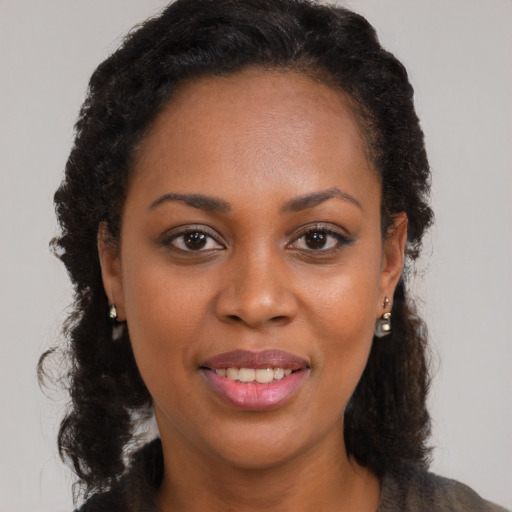 Joyful black young-adult female with long  brown hair and brown eyes