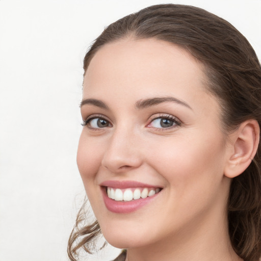 Joyful white young-adult female with long  brown hair and grey eyes