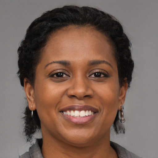 Joyful black adult female with medium  brown hair and brown eyes