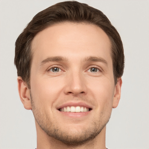 Joyful white young-adult male with short  brown hair and grey eyes