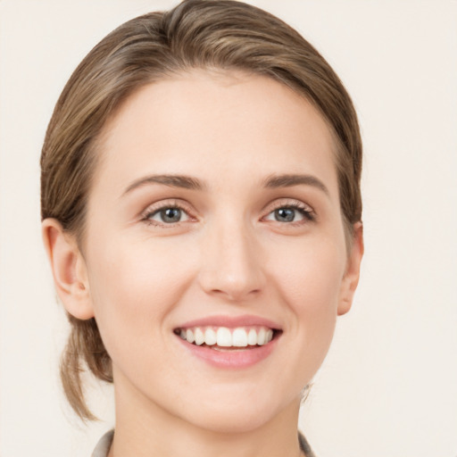 Joyful white young-adult female with medium  brown hair and grey eyes