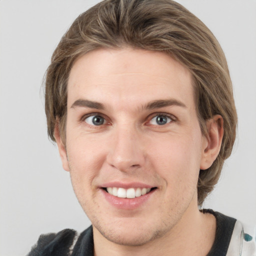 Joyful white young-adult male with medium  brown hair and grey eyes