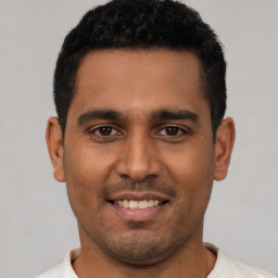 Joyful latino young-adult male with short  brown hair and brown eyes