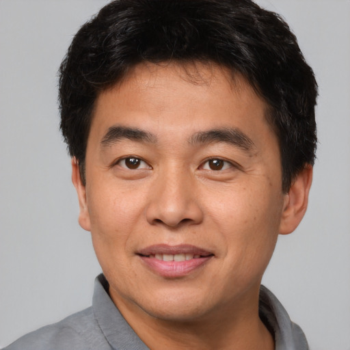 Joyful asian young-adult male with short  brown hair and brown eyes