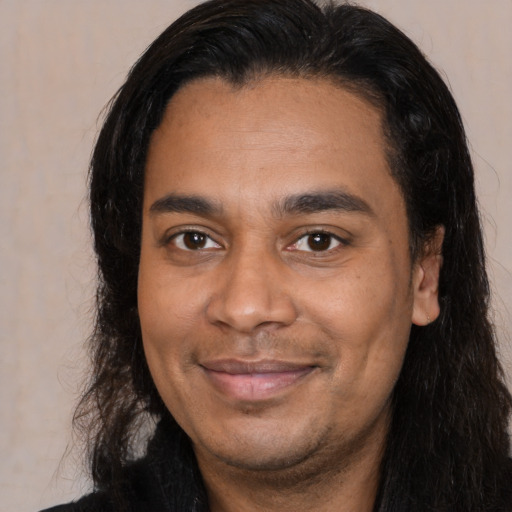 Joyful latino young-adult male with long  brown hair and brown eyes