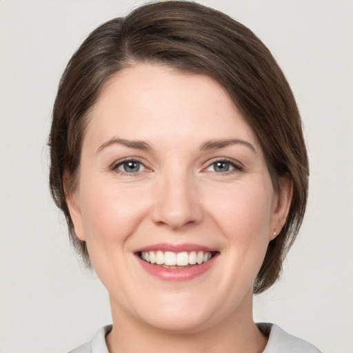 Joyful white young-adult female with medium  brown hair and grey eyes