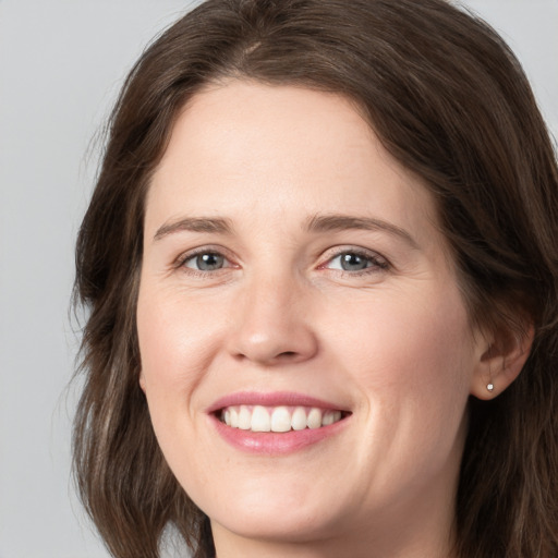 Joyful white young-adult female with medium  brown hair and grey eyes