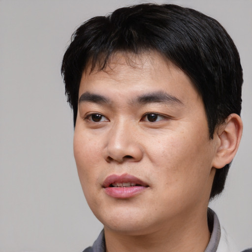 Joyful asian young-adult male with short  black hair and brown eyes