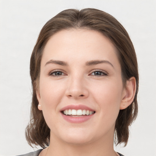 Joyful white young-adult female with medium  brown hair and grey eyes