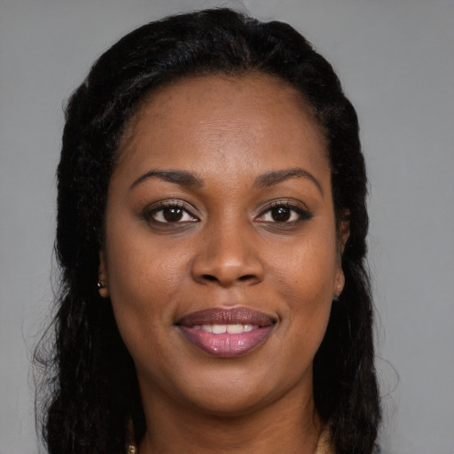 Joyful black young-adult female with long  brown hair and brown eyes