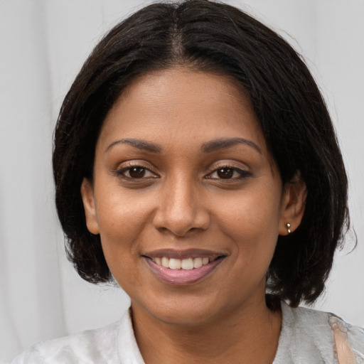 Joyful black young-adult female with medium  brown hair and brown eyes