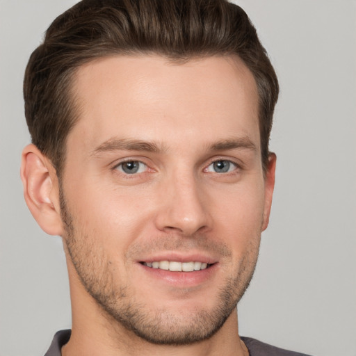 Joyful white young-adult male with short  brown hair and grey eyes