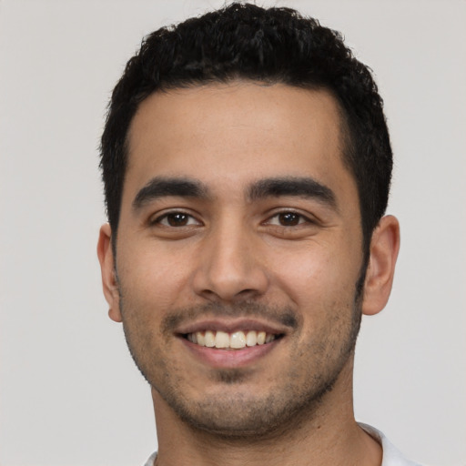 Joyful latino young-adult male with short  black hair and brown eyes
