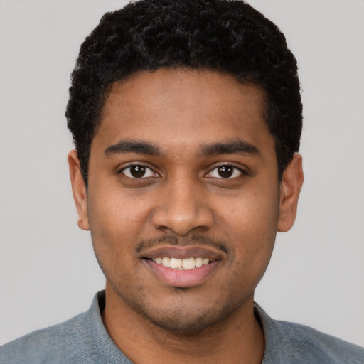 Joyful black young-adult male with short  black hair and brown eyes