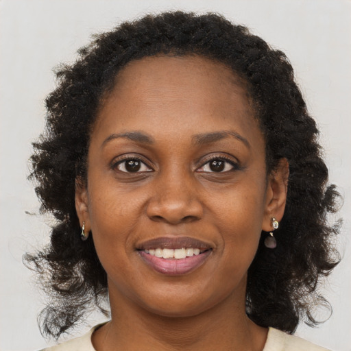 Joyful black young-adult female with long  brown hair and brown eyes