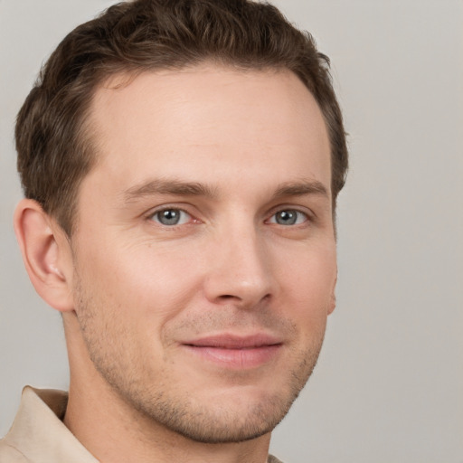 Joyful white young-adult male with short  brown hair and grey eyes