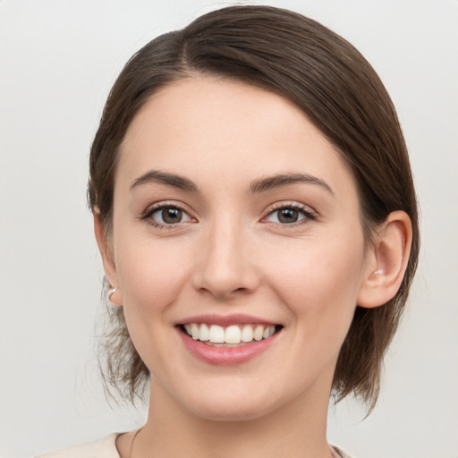 Joyful white young-adult female with medium  brown hair and grey eyes