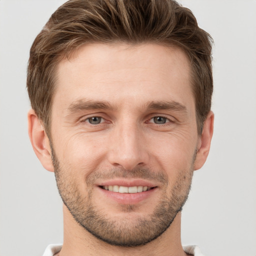 Joyful white young-adult male with short  brown hair and grey eyes