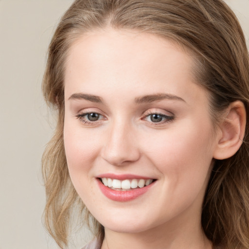 Joyful white young-adult female with long  brown hair and blue eyes